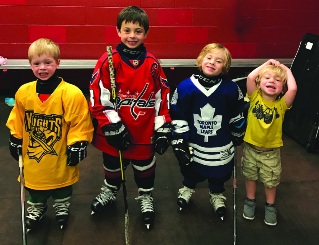 four kids wearing hockey jerseys and smiling